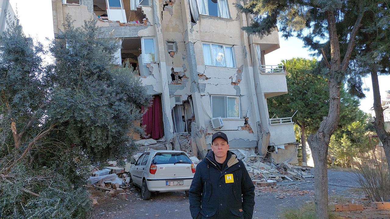Ein Hilfswerk-Mitarbeiter steht vor einem schwer beschädigten Haus in Hatay, Türkei.